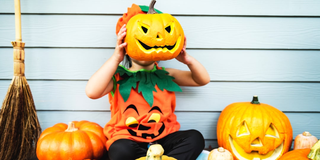 Image of a child holding a smiling carved pumpkin