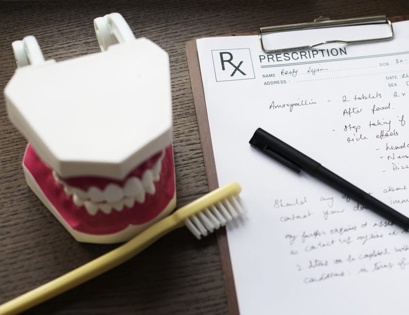 denture model with a yellow toothbrush beside a written medical treatment plan
