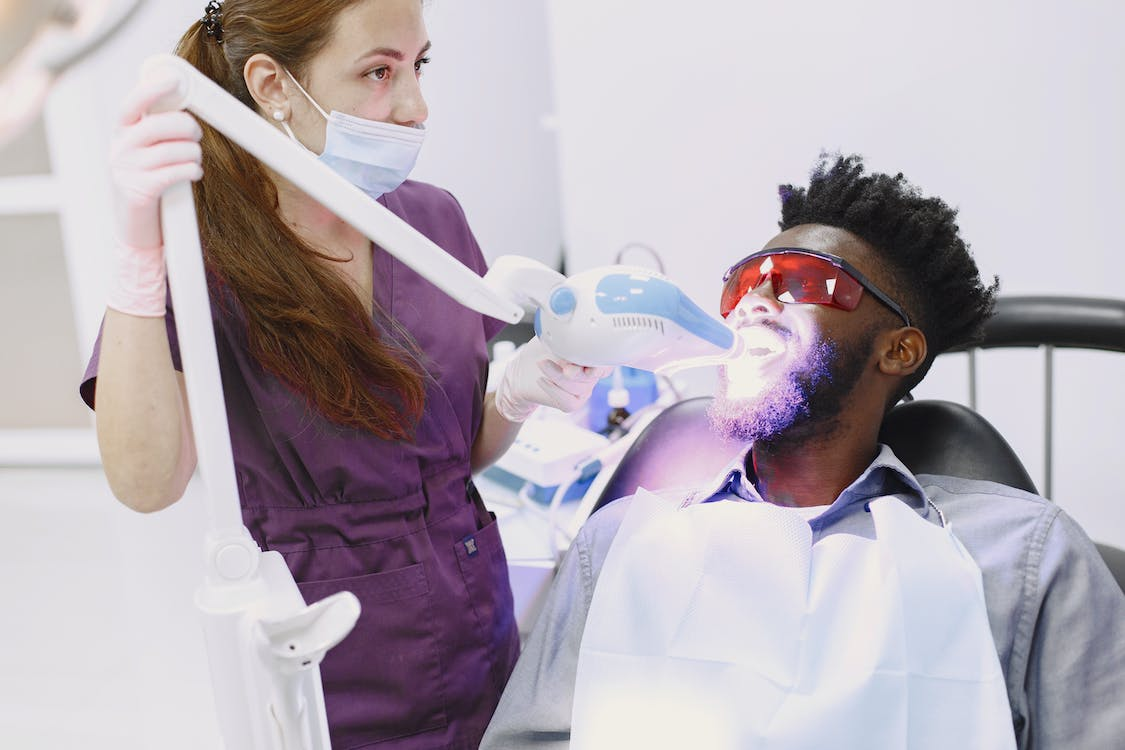 a dentist whitening a man's teeth 