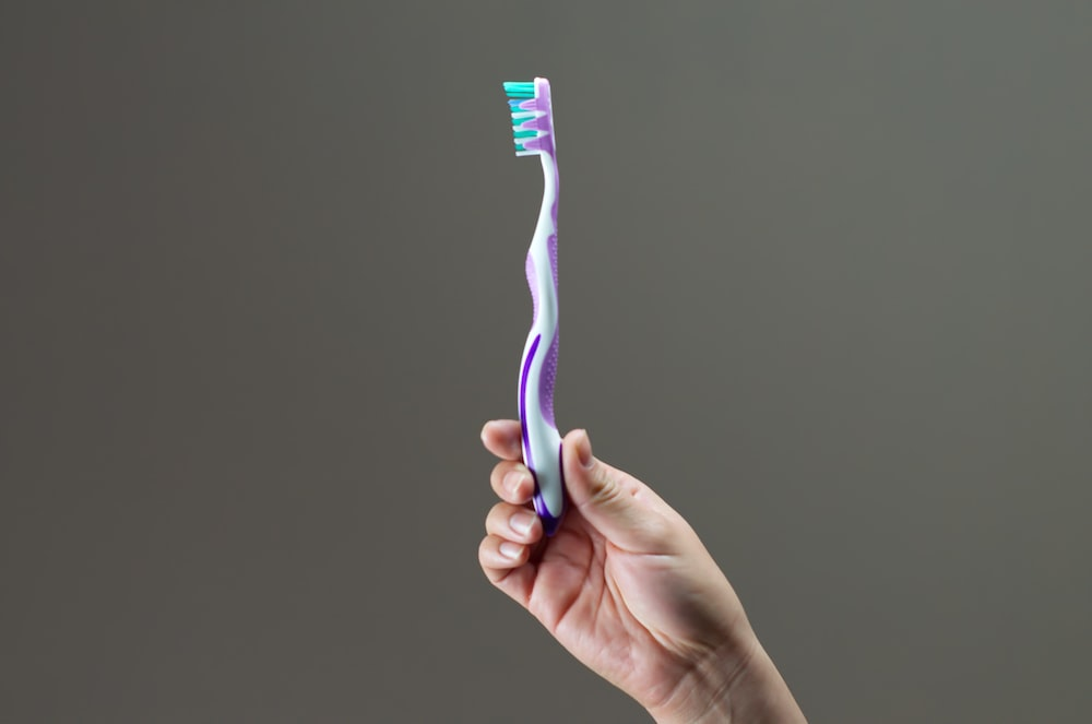 A person holding a toothbrush in their hand